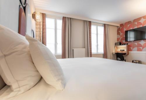a bedroom with a large white bed with windows at Hôtel de L'Esperance in Paris