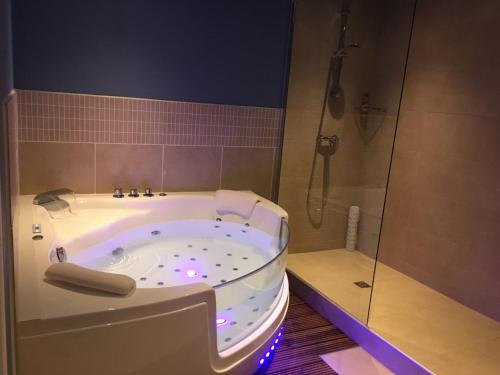 a bathroom with a large tub and a shower at Hôtel Des Argousiers in Ambleteuse