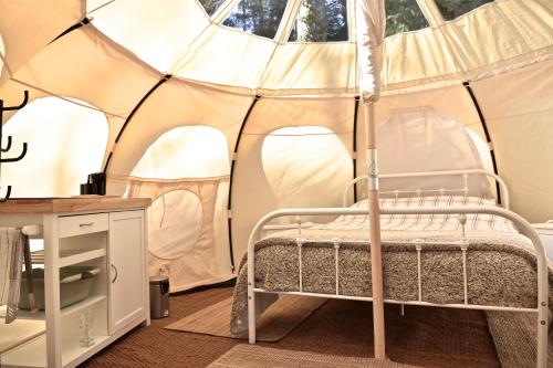 een slaapkamer met een bed in een tent bij Glamping at Camping La Source in Saint-Pierre-dʼArgençon
