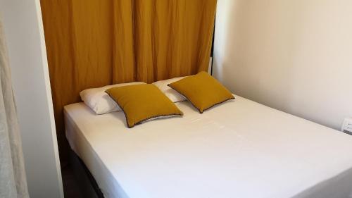 - un lit blanc avec 2 oreillers jaunes dans l'établissement Dana centre mer 16, à Nice