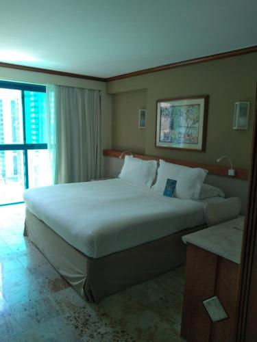 a bedroom with a large white bed with a window at Hotel Atlante Plaza in Recife