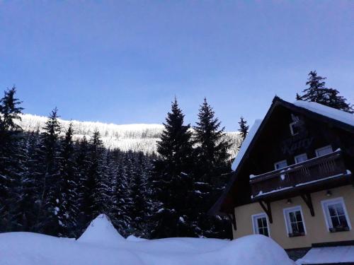 a house in the snow with a mountain in the background at Pension Katty in Špindlerův Mlýn