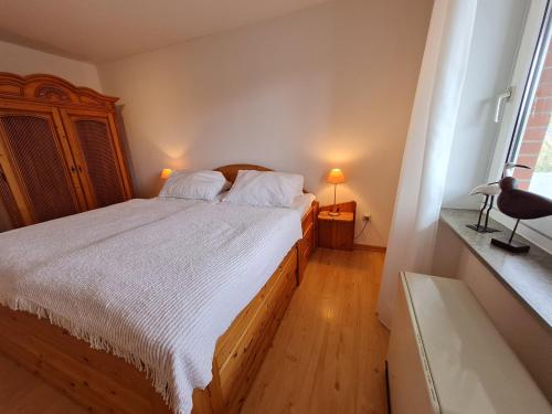 a bedroom with a bed with white sheets and a window at Wattwurm in Wyk auf Föhr