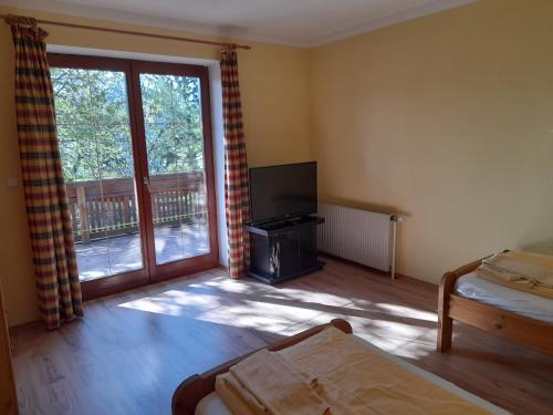 a living room with a television and a sliding glass door at Apartments Himmelreich in Ternitz