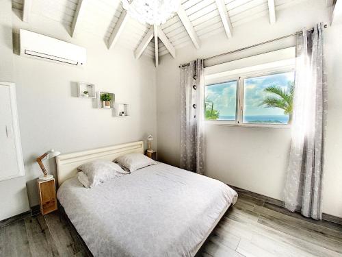 a white bedroom with a bed and a window at Villa La Guapa, sea view, private pool, 5 min from the beach in Saint Martin