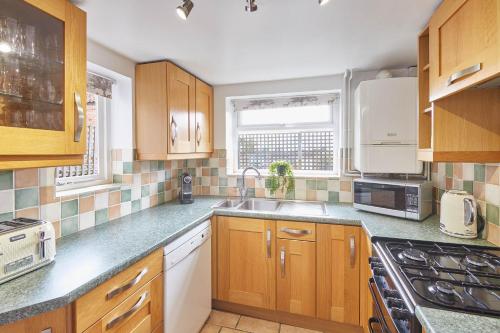 een keuken met houten kasten en een wastafel bij Host & Stay - Dove Grey, 25 West End in Kirkbymoorside