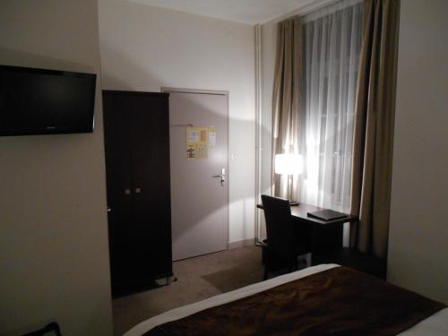 a hotel room with a bed and a desk and a mirror at Hotel de Montaulbain in Verdun