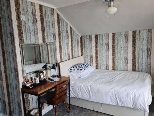 1 dormitorio con cama y escritorio con espejo en St.Ebba B&B, en Rothesay