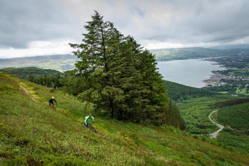 two people riding bikes on a grassy hill with a lake at Rostrevor Mountain Lodge - Glamping Pods - Revive Sauna & Hot Tubs in Rostrevor