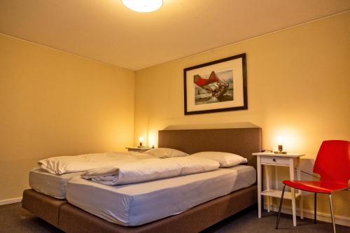 a bedroom with two beds and a red chair at Woonboot Sweltsje in Earnewâld