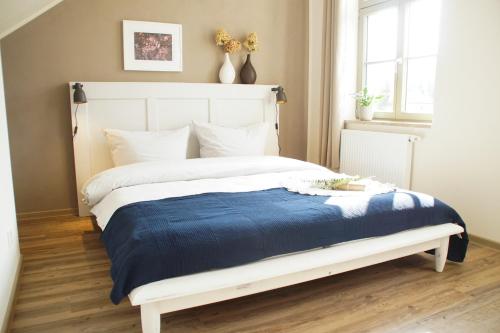 um quarto com uma cama branca e um cobertor azul em Urlaubsfreude Biedermann Haus Blumenglück - Hortensie em Sebnitz