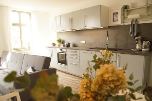 una cocina con armarios blancos y un sofá en una habitación en Urlaubsfreude Biedermann Haus Blumenglück - Hortensie en Sebnitz