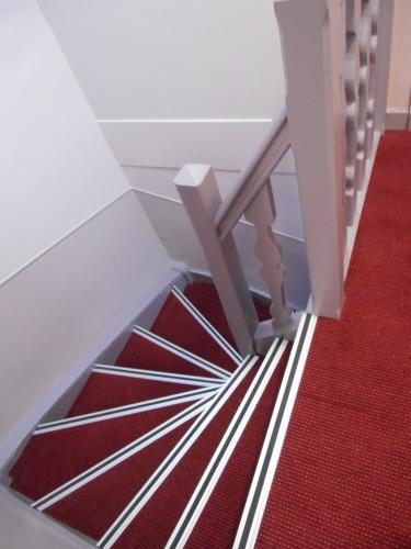 a stairwell with a red carpet and a white stair case at Hotel de Montaulbain in Verdun