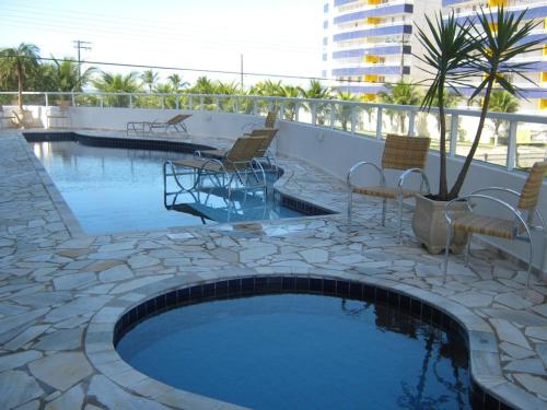 a swimming pool with chairs and a table on a patio at Apto Frente ao Mar in Bertioga