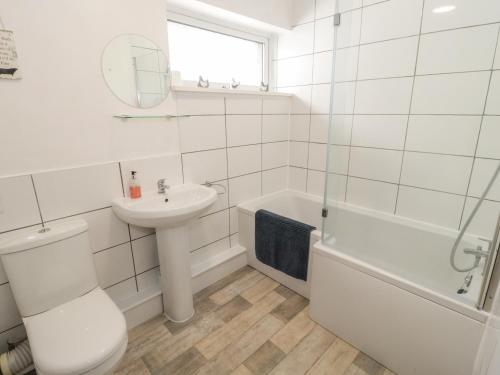 a white bathroom with a sink and a toilet and a tub at Glan Y Gors Cottage in Llangerniew