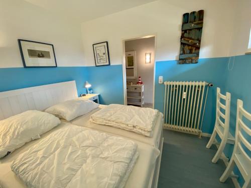 1 dormitorio con cama blanca y pared azul en Nord Nord West, en Wyk auf Föhr