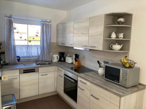 a kitchen with wooden cabinets and a microwave at Ferienhaus Heimathafen Neßmersiel in Neßmersiel