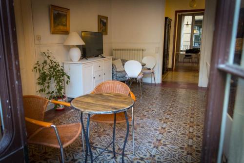 Habitación con mesa, sillas y TV. en B&B Placa Bell-Lloc, en Girona