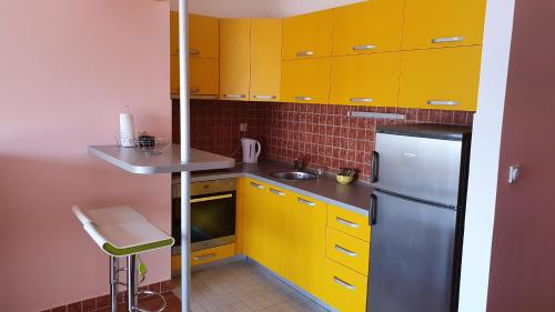 a kitchen with yellow cabinets and a stainless steel refrigerator at Sunrise Apartment in Baošići