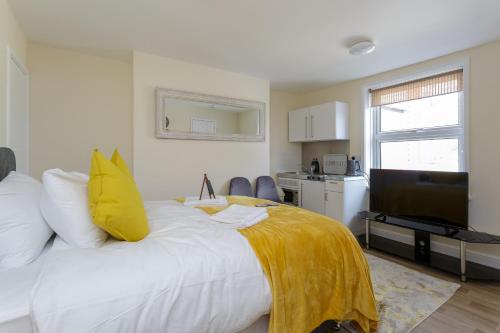 una camera da letto con un letto con una coperta gialla sopra di St Mary's - Modern Central Huge Studio Apartments a Southampton