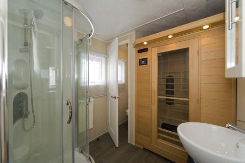 een badkamer met een glazen douche en een wastafel bij Bungalette Sauna 4p in Zuna