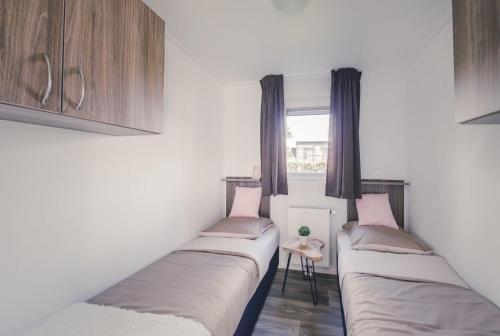 eine Reihe von Betten in einem Zimmer mit Fenster in der Unterkunft Buzzard 4 persons in Rijssen