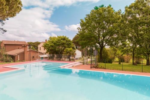 une grande piscine bleue avec des arbres en arrière-plan dans l'établissement Green Hill Apartments - Happy Rentals, à Castiglione del Lago