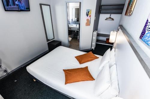 a bedroom with a bed with white sheets and orange pillows at Hôtel de Champagne in Angers