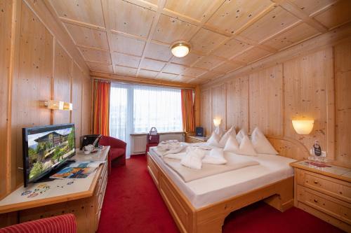 a bedroom with a large bed and a television at Hotel Latini in Zell am See