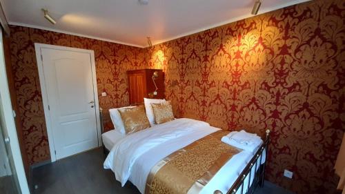 a bedroom with a bed and a wall with wallpaper at Bosdam Budget Rooms in Beveren