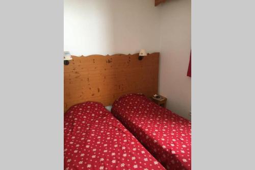- un lit avec des draps rouges et une tête de lit en bois dans l'établissement Puy St Vincent 1800 - appt 6 pers - près des pistes, à Puy-Saint-Vincent