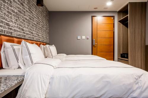 a large white bed in a room with a brick wall at San Chiao Hotel in Daxi