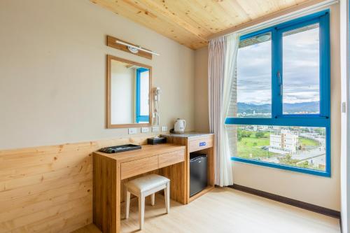 um quarto com uma secretária de madeira e uma janela em San Chiao Hotel em Daxi