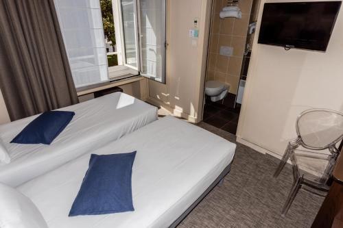 two beds with blue pillows in a hotel room at Hôtel de Champagne in Angers