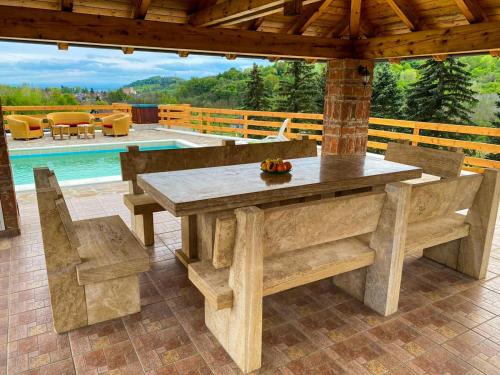 a wooden table and chairs on a patio with a pool at Le Ranch in Cernik
