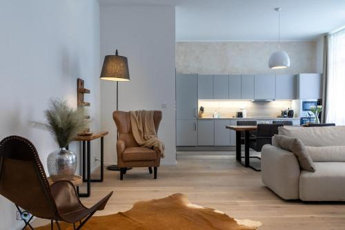 a living room with a couch and chairs and a kitchen at Sting Old Town Ostrava in Ostrava