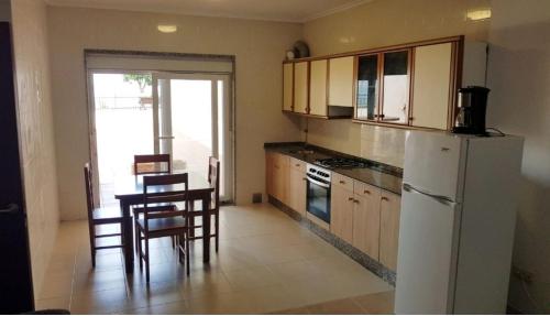 eine Küche mit einem weißen Kühlschrank sowie einem Tisch und Stühlen in der Unterkunft Casa do Castillo in Fisterra