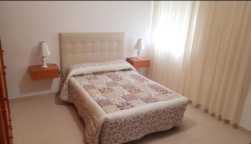 1 Schlafzimmer mit einem Bett mit einer Decke und 2 Lampen in der Unterkunft Casa do Castillo in Fisterra