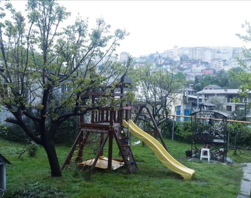 a playground with a slide next to a tree at Уютные апартаменты на ул Пионерская in Sochi