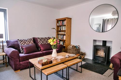 a living room with a purple couch and a fireplace at Finest Retreats - Charnwood in Lewannick