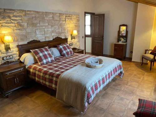 una camera con un grande letto e un muro di pietra di Casa Rural La Tayuela a Luanco