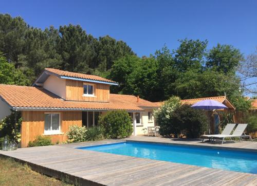 a villa with a swimming pool and a house at Maison l'heure bleue in Lanton