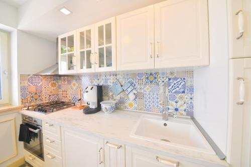 a kitchen with white cabinets and a sink at Belgodere di Mezzavia Apartments in Ischia