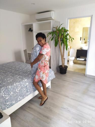 a woman in a dress standing next to a bed at La Aldea in Santo Domingo