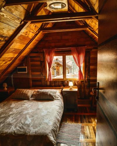 a bedroom in a log cabin with a bed and a window at Imanje Jelaš in Slunj
