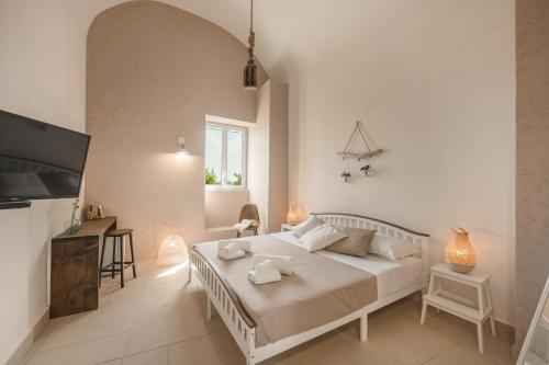 a white bedroom with a bed and a tv at Cala Cala Rooms,Restaurant & Farm Experience in Procida