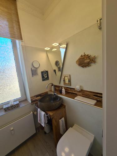 La salle de bains est pourvue d'un lavabo, de toilettes et d'un miroir. dans l'établissement Ferienwohnung BEACHHOUSE, à Cuxhaven