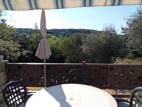 an umbrella and a table and chairs on a patio at Les Lauriers Roses in Salavas
