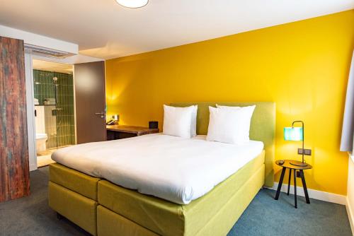 um quarto com uma cama grande e uma parede amarela em Boutique Hotel Zaan em Zaandijk