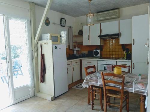 a kitchen with a table and a white refrigerator at Les Lauriers Roses in Salavas